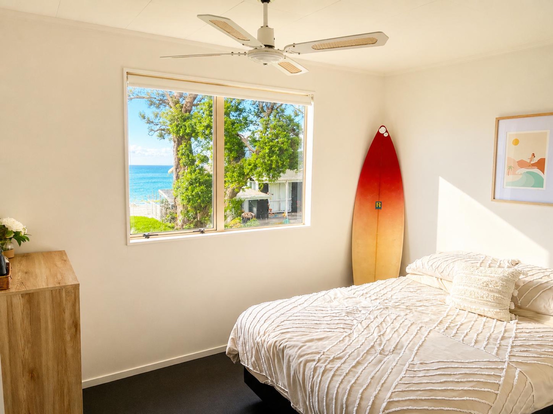 Queen bedroom with a glimpse of blue water through the window