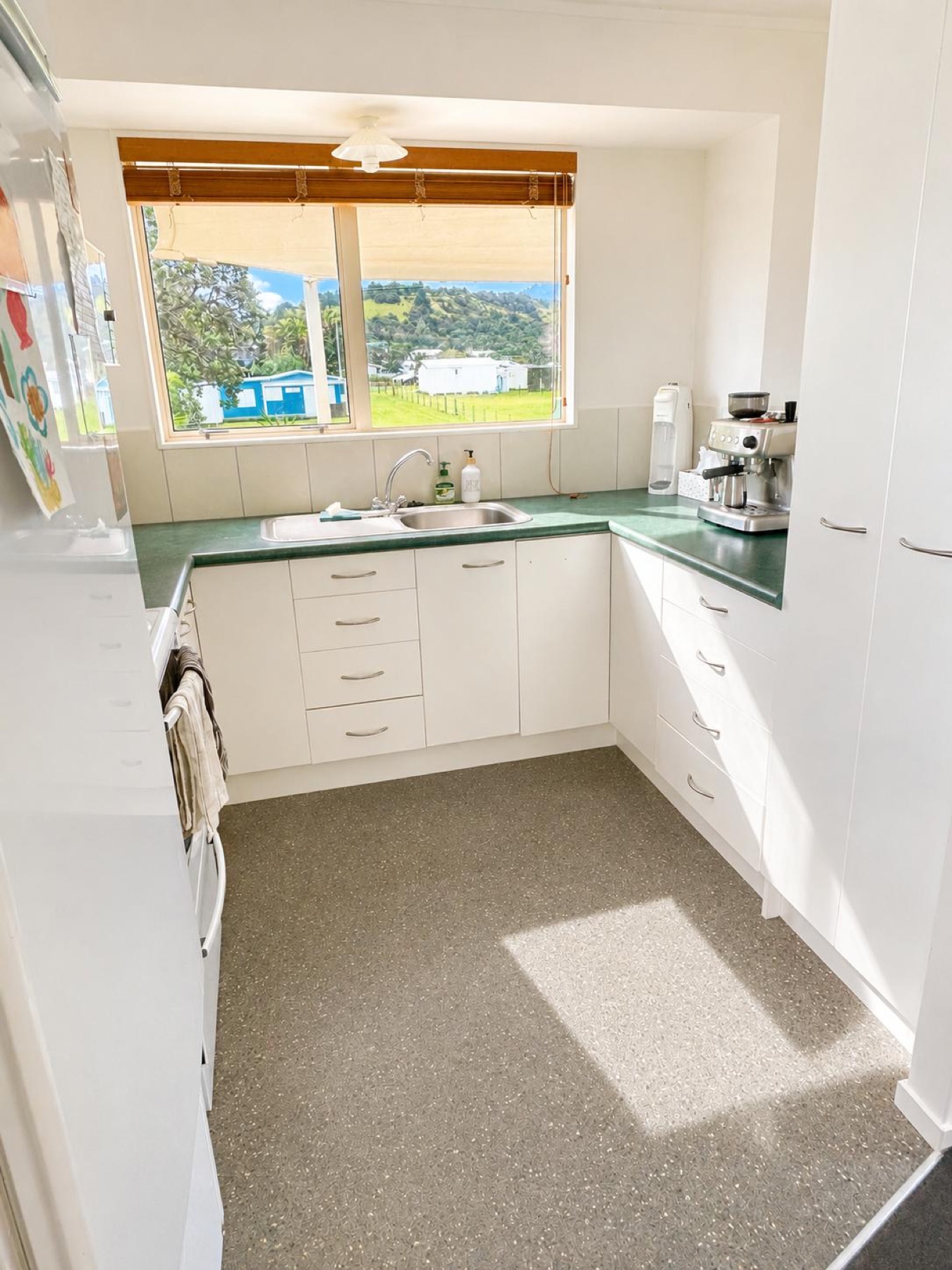 White kitchen with a green worktop and window over the sink